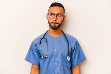 Young hispanic nurse man isolated on white background confused, feels doubtful and unsure.