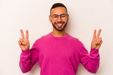 Naklejka premium Young hispanic man isolated on white background showing victory sign and smiling broadly.