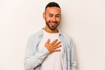 Young hispanic man isolated on white background laughs out loudly keeping hand on chest.