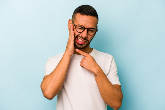 Young hispanic man isolated on blue background having a strong teeth pain, molar ache.