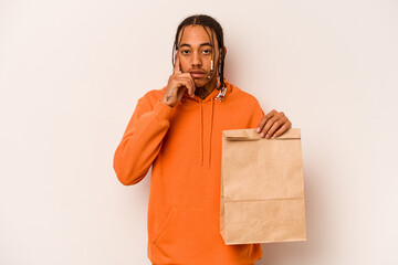 Young African American man holding takeaway bag isolated on white background pointing temple with finger, thinking, focused on a task.