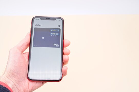 Apple Pay brand digital wireless pay concept - hand with Apple iphone with wallet on diplay