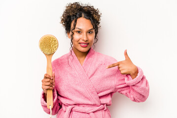 Young hispanic woman holding a back scratcher isolated on white background person pointing by hand to a shirt copy space, proud and confident