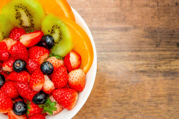 Fresh fruits concept, Fruits salad consist of kiwi and assorted berry in bowl on wooden background