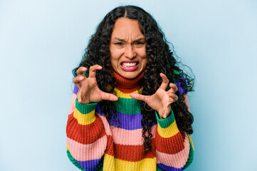 Young hispanic woman isolated on blue background upset screaming with tense hands.