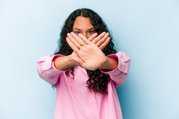 Young hispanic woman isolated on blue background doing a denial gesture