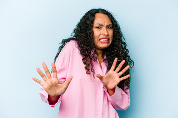Young hispanic woman isolated on blue background rejecting someone showing a gesture of disgust.