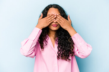 Young hispanic woman isolated on blue background afraid covering eyes with hands.
