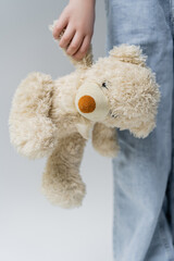 cropped view of child with teddy bear isolated on grey.