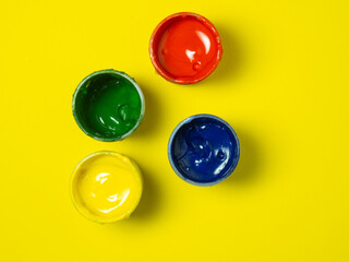Jars of paint on a yellow background. Banks of gouache.  Creative background. Artist's workshop.