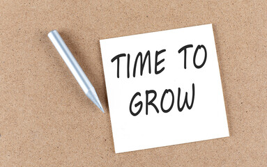 TIME TO GROW text on sticky note on cork board with pencil ,