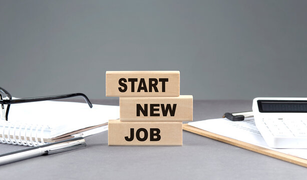 START NEW JOB text on wooden block with notebook,chart and calculator, grey background