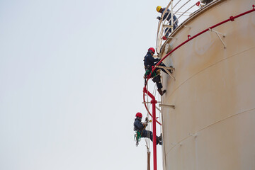 Male worker rope access height safety inspection of thickness storage oil