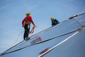 Male two workers rope access height safety connecting with eight knots safety harness, clipping into roof dome construction site oil tank.