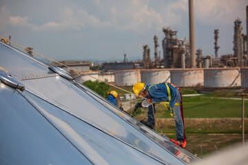 Male workers rope access height safety connecting with a knot safety harness, clipping into roof construction site oil tank dome
