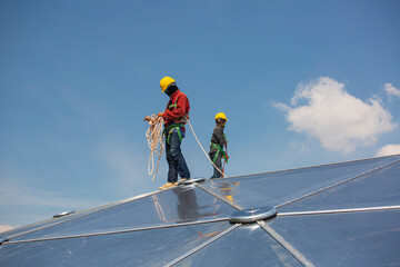 Male two workers rope access height safety connecting with eight knots safety harness, clipping into roof dome construction site oil tank.