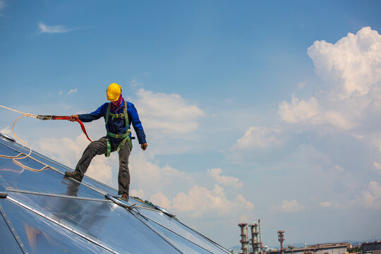 Male workers rope access height safety connecting with a knot safety harness, clipping into roof construction site oil tank dome