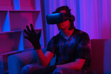 Metaverse technology concept, Man wear VR goggles and glove to making gesture while playing games