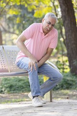 Naklejka na ściany i meble Senior man suffering from knee pain at park