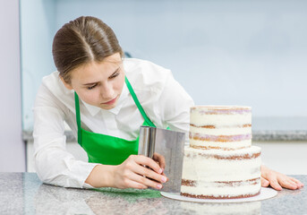 Confectioner makes a wedding cake with white cream  using a  cooking spatula