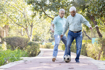 Two senior man having fun while playing football at park