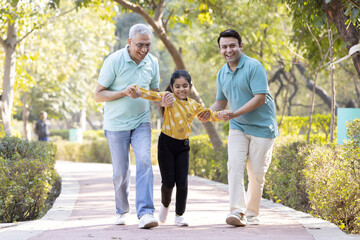 Cheerful senior man having fun while playing with son and granddaughter at park