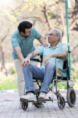 Young man assisting a senior man in a wheelchair at park