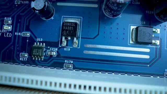 Top view of computer motherboard chip in blue light. Detail of electronic components on PC motherboard. Motherboard computer electrical circuit with cip, slots, microchip and microprocessors. Close up