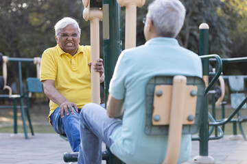 Two senior man doing leg exercise on leg press machine in open air gym at park