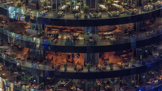Dubai marina waterfront and building with different restaurants at each floor aerial night timelapse.