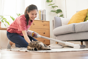 Happy asian young housekeeper woman using vacuum cleaning, cleaner to remove dust, hair or fur on...