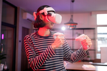 relax casual Asian adult Man Wearing Virtual Reality Headset and Holding Controllers Plays in a boxing sport Video Game at Home. Playing VR active sport game online in the Living Room with rgb lightin