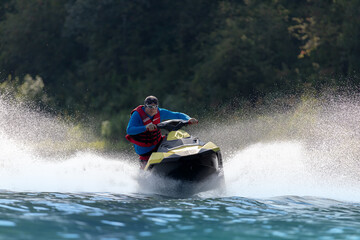 An extreme guy rides a sports jet ski on a mountain river. entertainment on a high-speed boat on the water with big splashes. Summer tourism and recreation on the water