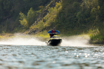 An extreme guy rides a sports jet ski on a mountain river. entertainment on a high-speed boat on...
