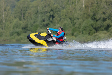 A guy in bright clothes rides a jet ski on the lake. entertainment on a high-speed boat on the water with big splashes. Summer tourism and recreation on the water
