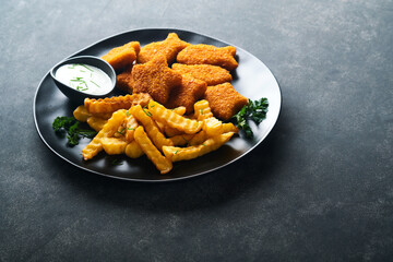 Fish Chips british fast food. Fish Sticks with french fries set on black plate on black table background. Traditional British authentic street food or takeaway food. Mock up with space for text.