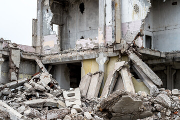 A pile of debris in the form of concrete slabs, piles, bricks on the background of the structure of the destroyed building. Background. Focus on the foreground