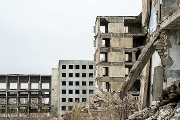 View of the destroyed buildings with concrete rubble against the background of a part of the...