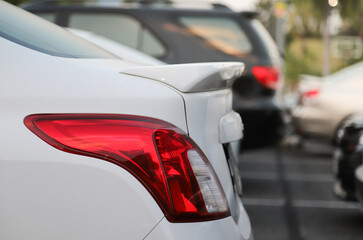 Closeup of rear, back car-light of white car parking in outdoor parking area.