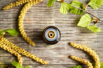 A dropper bottle of essential oil with birch branches