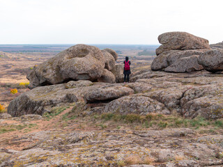 Traveler hiker woman with smartphone and backpack raincoat on mountain summit. Girl backpacker taking picture of scenic landscape. Active Lifestyle tourism. Solo Travel hiking extreme outdoor activity