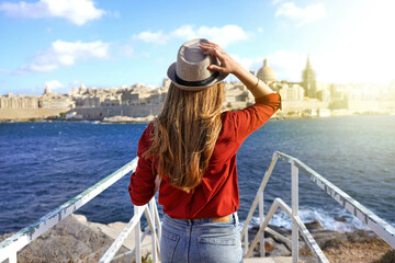 Tourism in Europe. Back view of traveler girl walking on stairs enjoying view of Valletta city,...
