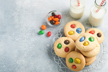 Fototapeta na wymiar Homemade cookies with colorful chocolate candies and milk. Stack of shortbread cookies with multi colored candy on plate with bottle of milk on light gray background. Baby food concept. Copy space.