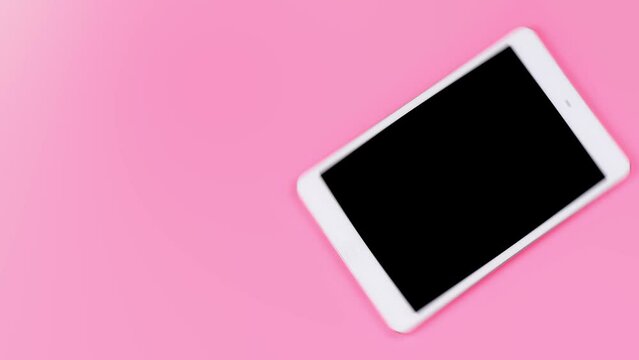 A simple pink background with a rotating tablet in a modern style. Background with empty space for text on the topic of modern technology.