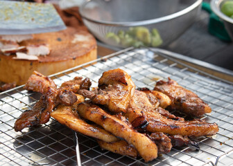 Grilled marinated barbecue pork neck with seasoned sauce on the grill at street food in Thailand. Asian Thai street food concept