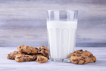 A stack of chocolate chip cookies lies near a glass of milk. Calcium-rich milk.