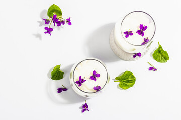Vegan panna cotta dessert with fresh violet flower. Striped very peri color food, trendy stand