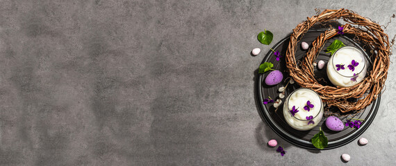 Obraz na płótnie Canvas Happy Easter festive composition. Vegan panna cotta dessert with fresh violet flower