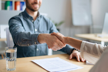 Cropped view of human resources manager shaking hands with successful vacancy applicant at office, closeup