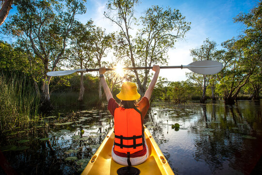 happy woman kayaking with kayak boat in nuture lake behind sea and beach before sunset time for relax and extreme water sport